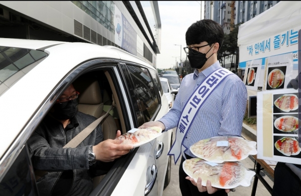 서울 동작구 노량진수산시장에 설치된 드라이브 스루 판매 부스에서 직원이 차 안의 고객에게 모둠회를 건네고 있다.