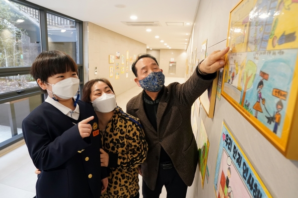 래미안미드카운티아파트에서 주최한 어린이 그림 공모전에서 대상을 수상한 김진우 어린이(사진 왼쪽)와 어머니가 래미안미드카운티 입주자대표회장과 함께 작품을 관람하고 있다