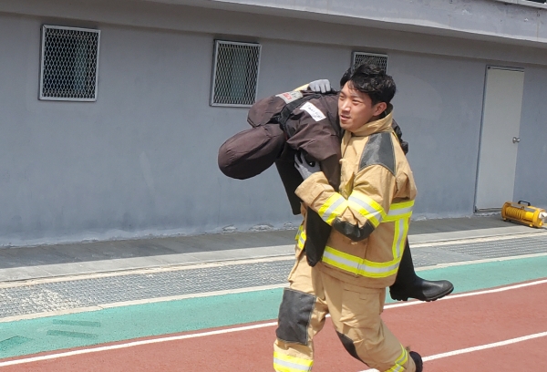 [인천시 최강소방관 선발대회에 출전한 한 소방대원이 70kg에 달하는 마네킹을 어깨에 메고, 코스를 뛰어가고 있다.]